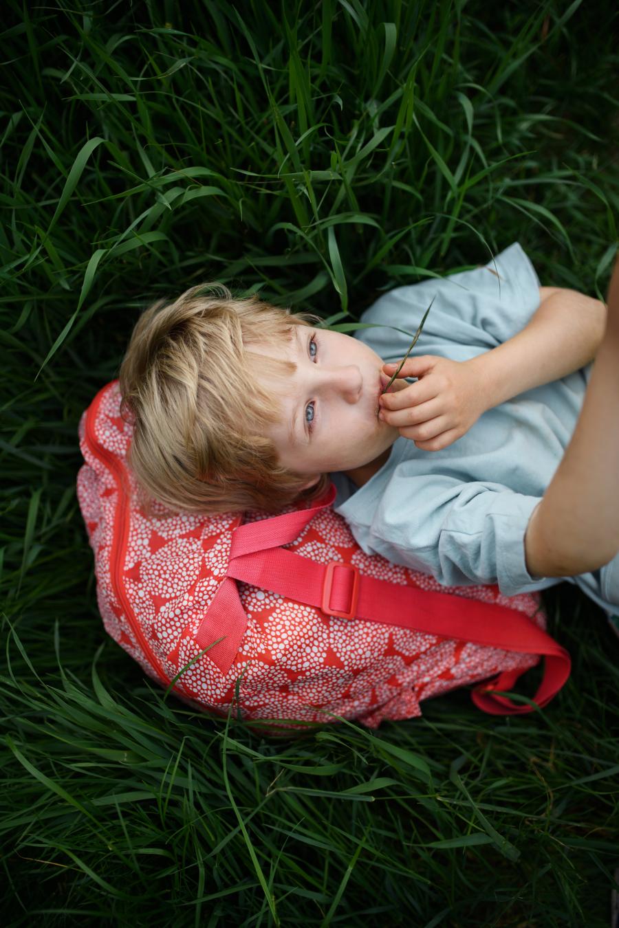 dreng i græs med skoletaske